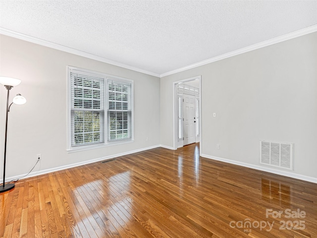 empty room with baseboards, visible vents, wood-type flooring, a textured ceiling, and crown molding