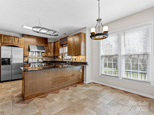 kitchen with stainless steel refrigerator with ice dispenser, a peninsula, wall chimney exhaust hood, decorative backsplash, and stove