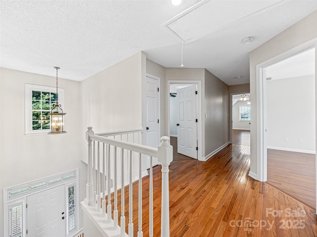 hall featuring an upstairs landing, attic access, a healthy amount of sunlight, and light wood finished floors