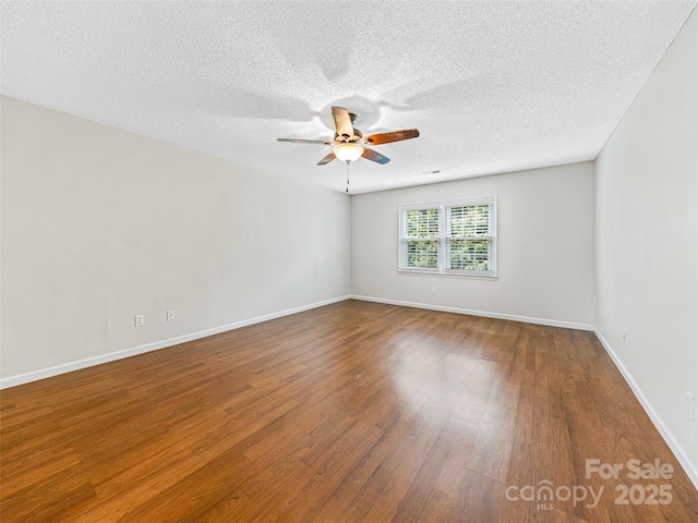 spare room featuring wood finished floors, a ceiling fan, baseboards, and a textured ceiling