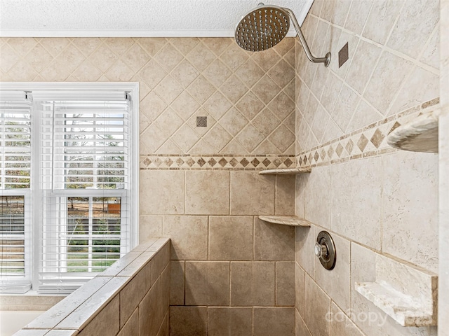 full bathroom featuring a tile shower, a textured ceiling, and ornamental molding