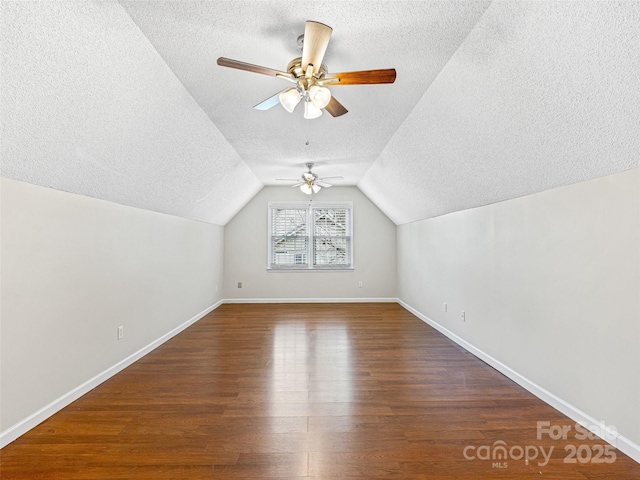 bonus room with wood finished floors, baseboards, ceiling fan, vaulted ceiling, and a textured ceiling