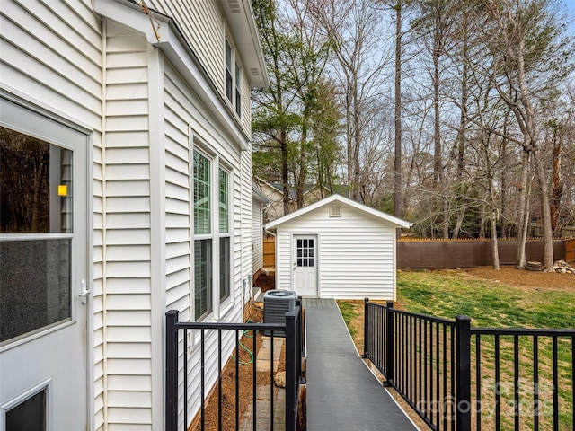 wooden deck with a storage shed, an outdoor structure, cooling unit, and fence