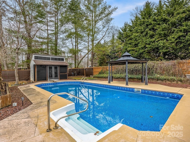 view of swimming pool with an outbuilding, a fenced in pool, a fenced backyard, a gazebo, and a storage structure