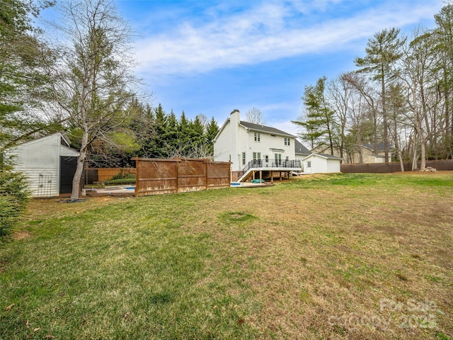 view of yard featuring a pool, an outdoor structure, a deck, and fence