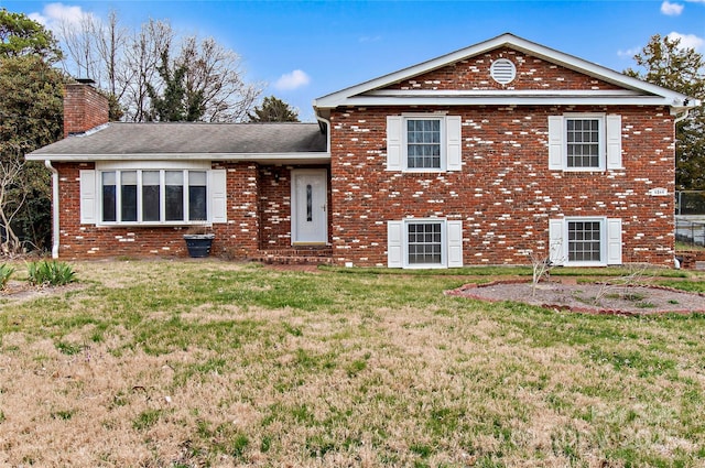 tri-level home featuring brick siding, a chimney, and a front lawn