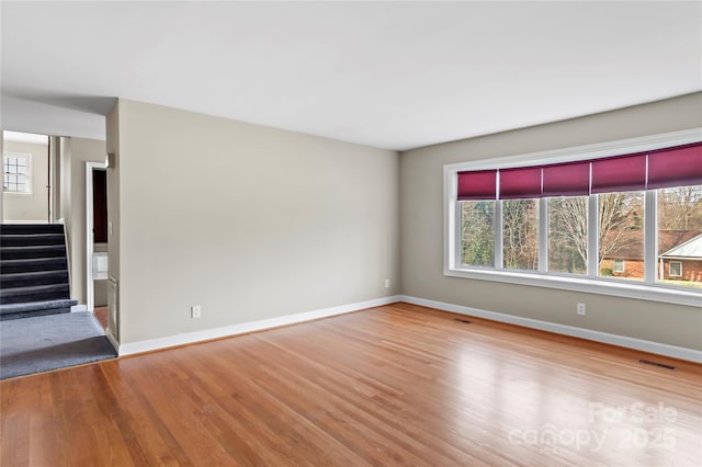 unfurnished room with visible vents, stairway, baseboards, and wood finished floors