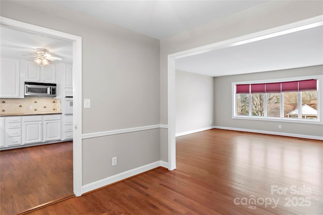 interior space featuring visible vents, baseboards, wood finished floors, and a ceiling fan