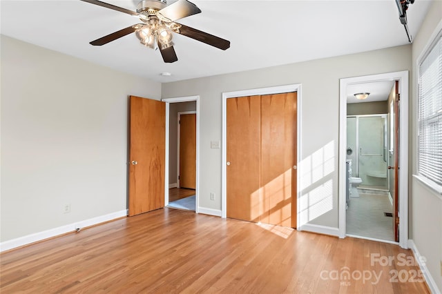 unfurnished bedroom featuring a closet, ensuite bath, light wood-type flooring, and baseboards