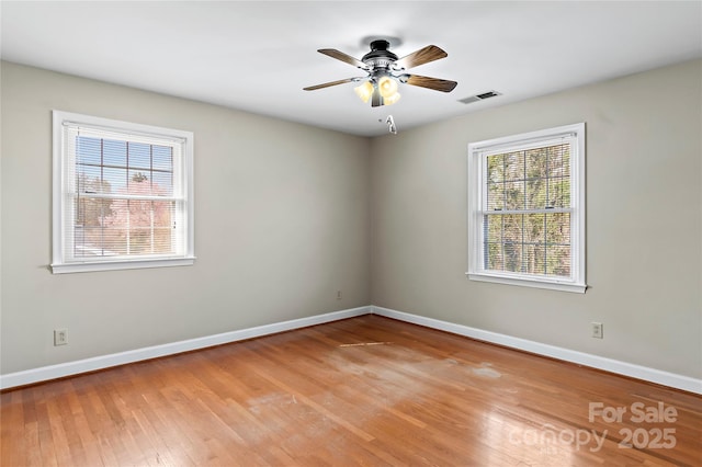 empty room featuring visible vents, baseboards, wood finished floors, and a ceiling fan