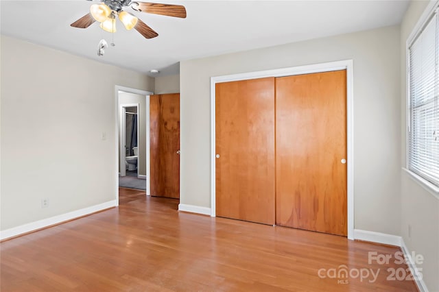 unfurnished bedroom featuring a ceiling fan, light wood-style floors, baseboards, and a closet