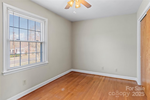 empty room with light wood-style floors, a ceiling fan, and baseboards