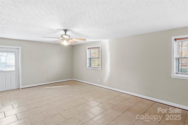 spare room with baseboards, a healthy amount of sunlight, a textured ceiling, and a ceiling fan