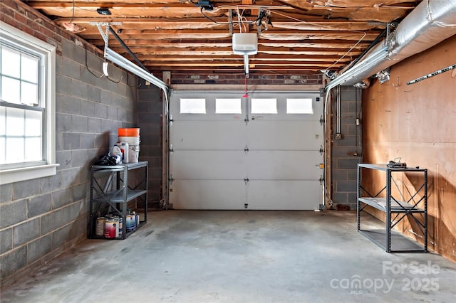 garage featuring concrete block wall and a garage door opener