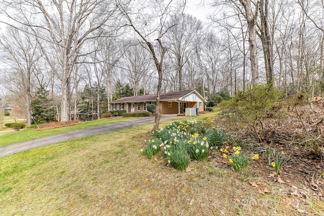 ranch-style home with a front yard, an attached carport, and driveway