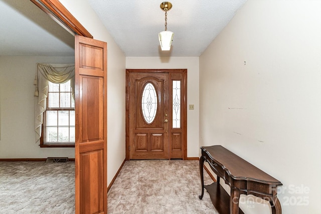 foyer with visible vents, light carpet, plenty of natural light, and baseboards