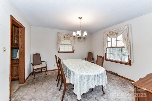 dining room with an inviting chandelier, baseboards, visible vents, and light carpet