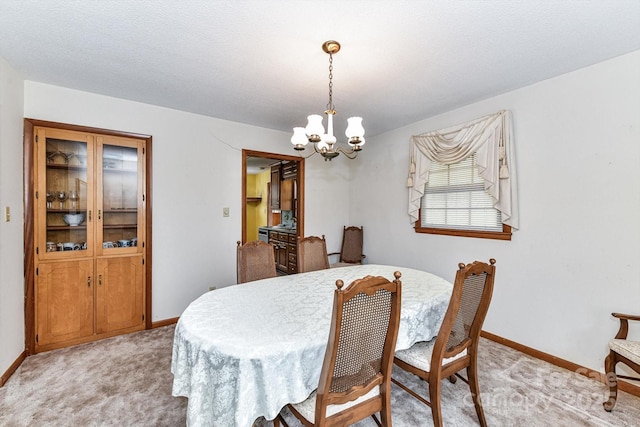 dining space featuring a chandelier, light colored carpet, and baseboards