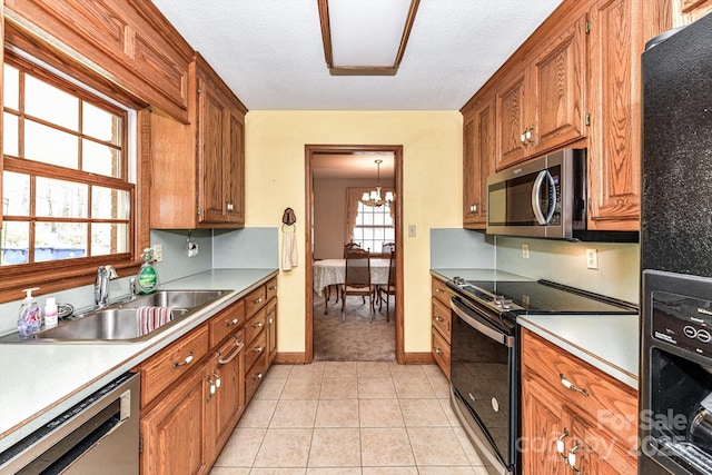 kitchen featuring an inviting chandelier, light tile patterned flooring, a sink, black appliances, and brown cabinets