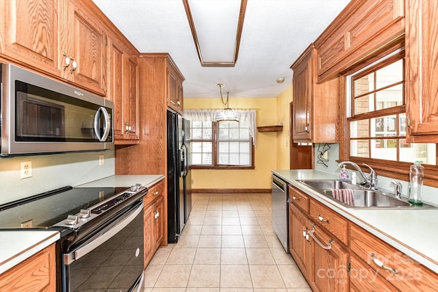 kitchen featuring light countertops, brown cabinets, appliances with stainless steel finishes, light tile patterned flooring, and a sink