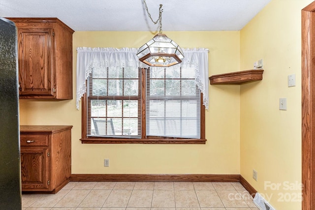 unfurnished dining area with light tile patterned floors, visible vents, and baseboards