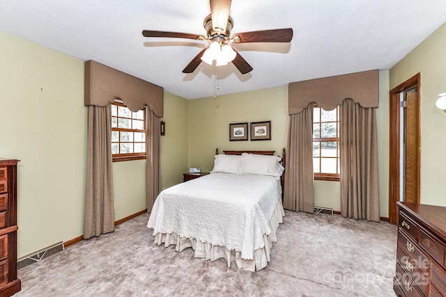 bedroom with visible vents, a ceiling fan, a textured ceiling, baseboards, and light colored carpet