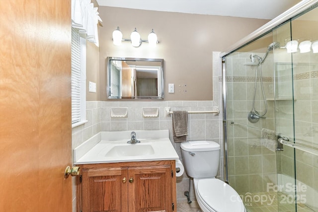 bathroom featuring a shower stall, tile walls, and vanity