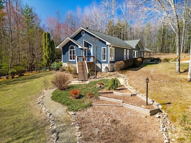 ranch-style home featuring a front yard, a vegetable garden, and a view of trees