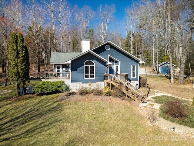 view of front facade featuring a deck, a chimney, stairs, and a front yard