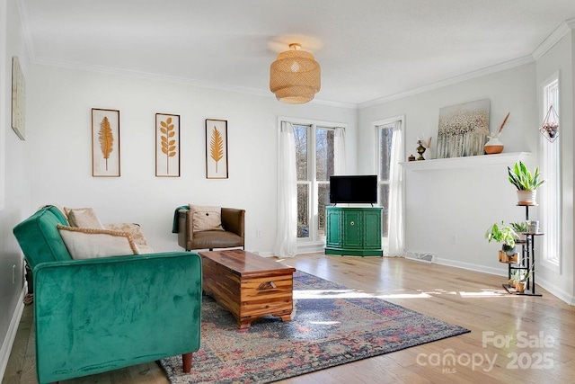 living area featuring crown molding, wood finished floors, visible vents, and a wealth of natural light