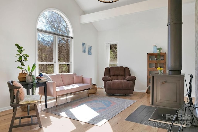 living room featuring a wealth of natural light, high vaulted ceiling, baseboards, and wood finished floors