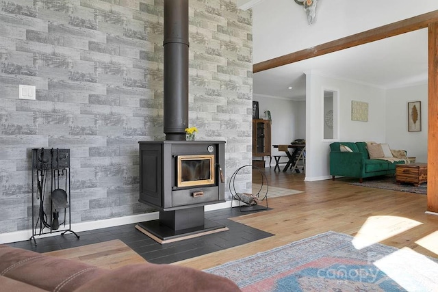 living room featuring a wood stove, wood finished floors, baseboards, and ornamental molding