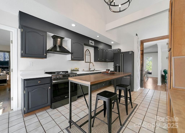 kitchen with gas stove, light tile patterned flooring, a sink, wall chimney exhaust hood, and black refrigerator with ice dispenser