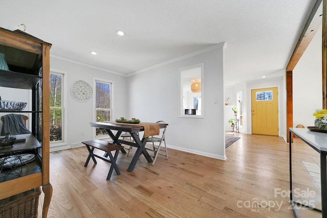 dining area with light wood-style flooring, crown molding, baseboards, and a healthy amount of sunlight