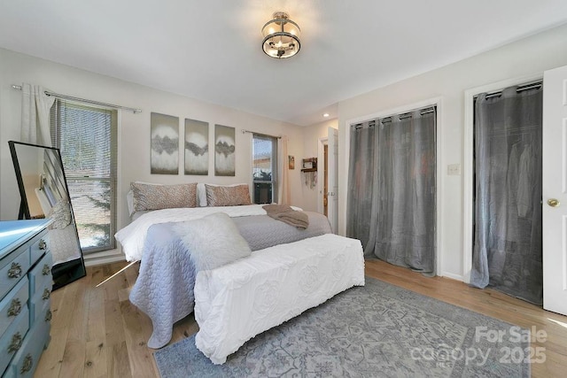 bedroom featuring light wood finished floors, multiple windows, and baseboards