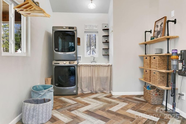 clothes washing area with baseboards, laundry area, and stacked washer / dryer