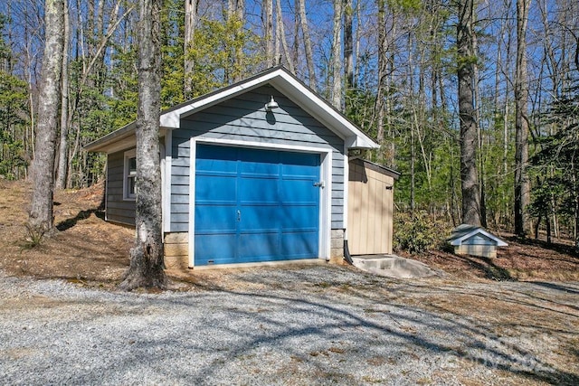 detached garage with a view of trees