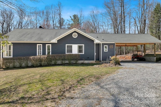 view of front of property with gravel driveway, an attached carport, and a front yard