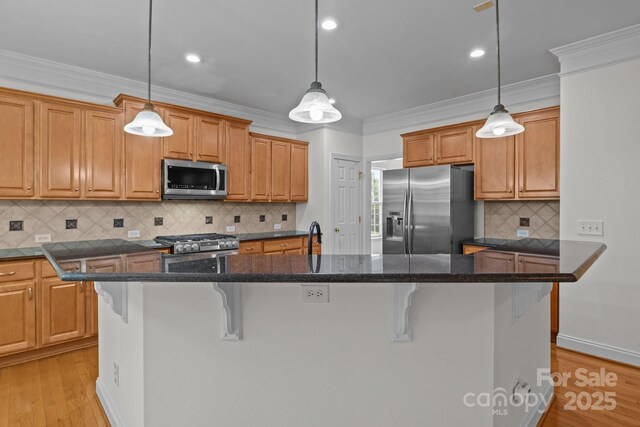 561 Keystone Ct NW, Concord, NC 28027 - kitchen featuring appliances with stainless steel finishes, a center island, a kitchen bar, light wood-style floors, and ornamental molding