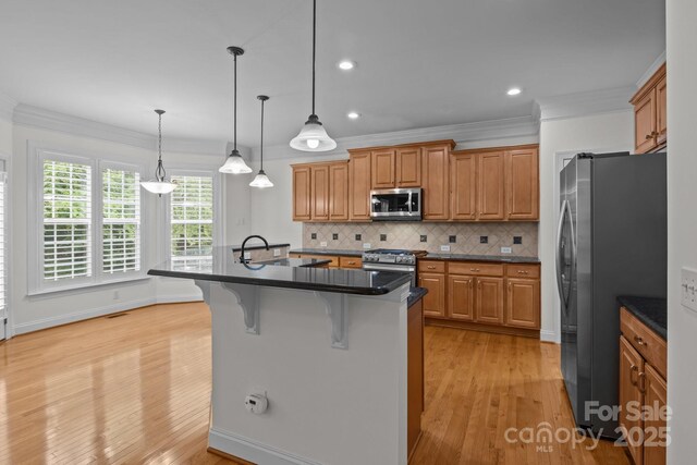 561 Keystone Ct NW, Concord, NC 28027 - kitchen with appliances with stainless steel finishes, dark countertops, a kitchen breakfast bar, light wood-style flooring, and ornamental molding