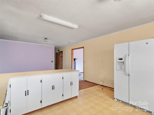 kitchen with light floors, white cabinets, light countertops, and white fridge with ice dispenser