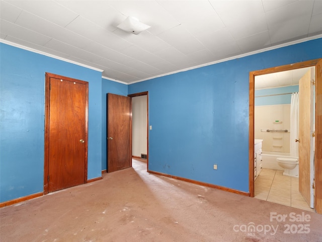 unfurnished bedroom with a closet, baseboards, connected bathroom, and ornamental molding