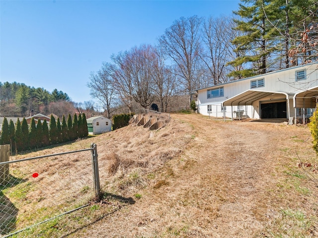 view of yard with a carport, a garage, and fence