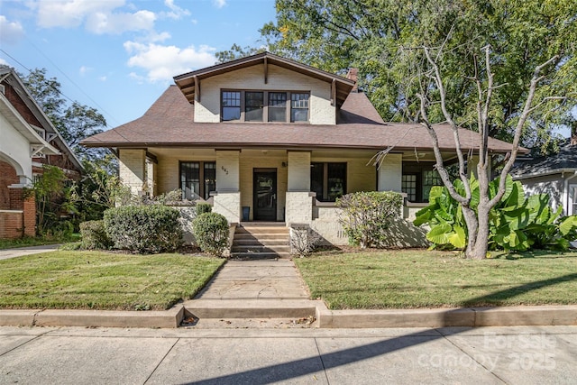 view of front of property featuring a front yard, covered porch, and brick siding