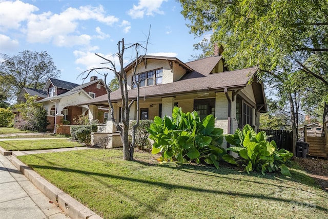 view of front of home featuring a front yard, fence, brick siding, and a chimney