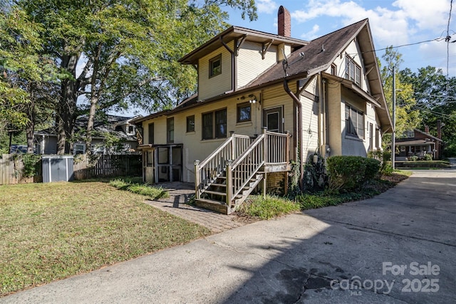 view of front of house with a front lawn, fence, and a chimney