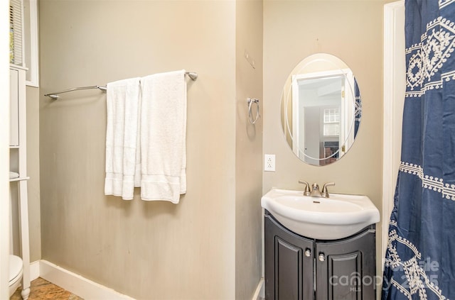 bathroom featuring baseboards, toilet, and vanity