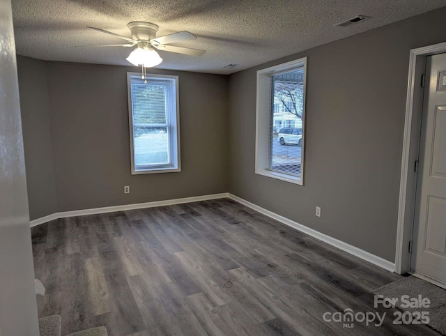 empty room with visible vents, a textured ceiling, baseboards, ceiling fan, and dark wood-style flooring