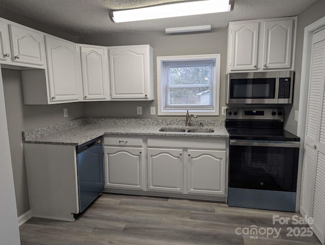 kitchen featuring white cabinets, light wood-style floors, appliances with stainless steel finishes, and a sink