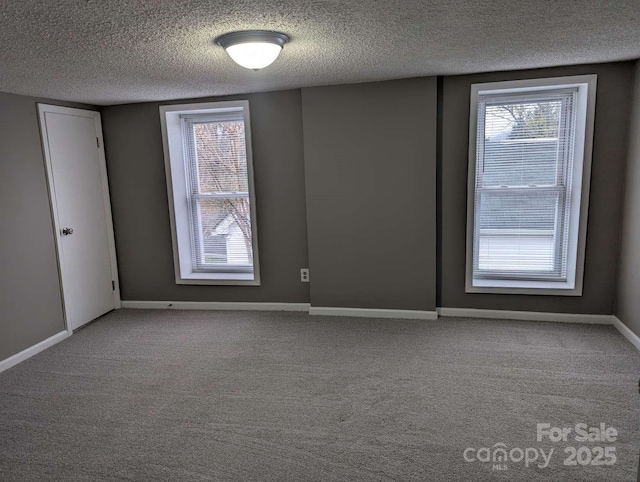 carpeted empty room with baseboards and a textured ceiling